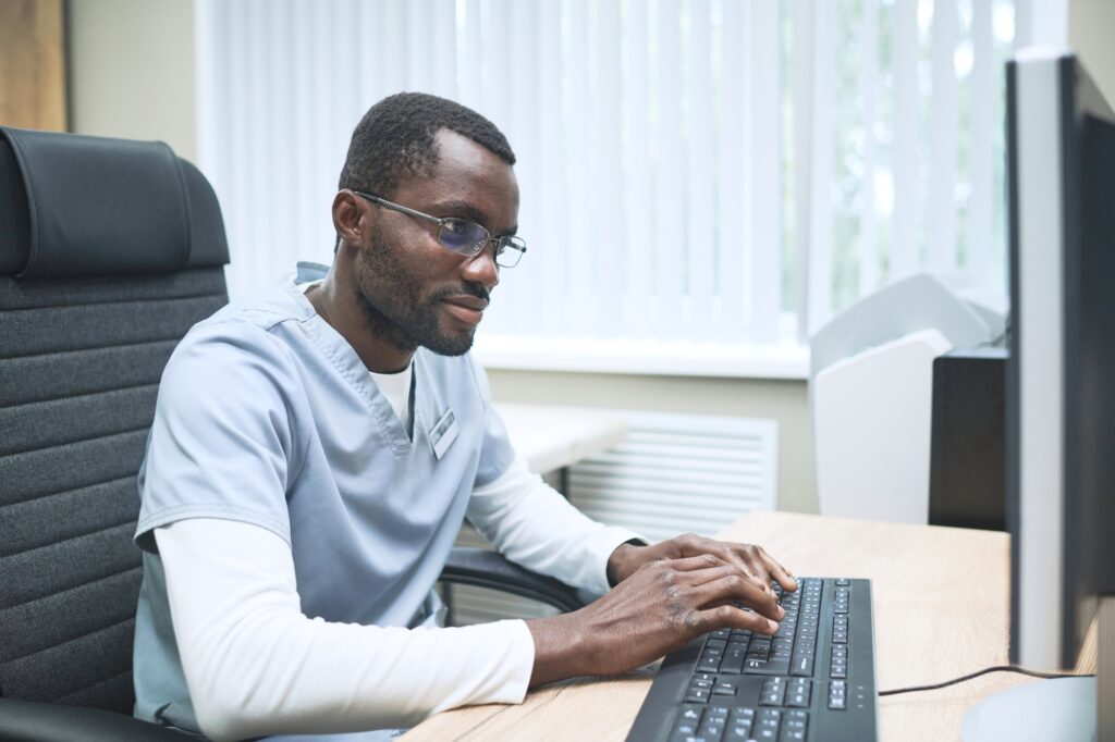 Busy Black doctor typing on computer